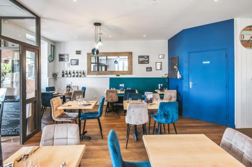 un restaurante con paredes azules y mesas y sillas de madera en L'Esplanade en Le Pellerin