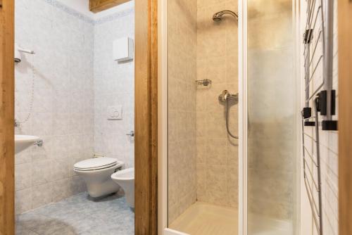 uma casa de banho com um WC e um chuveiro com uma porta de vidro em Appartamento Adamello 11 em Pinzolo