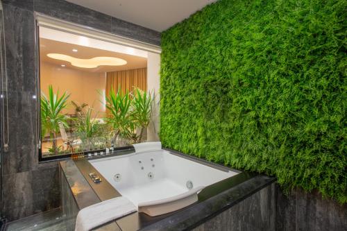 a bathroom with a green wall with a bath tub at Best Western Premier Ark Hotel in Tirana