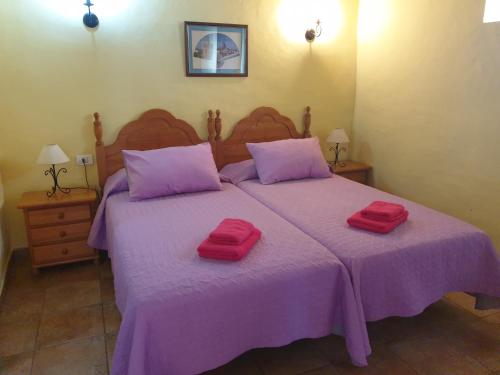 1 dormitorio con 1 cama morada y 2 toallas rojas. en Casa Rural Domingo Pio en Echedo