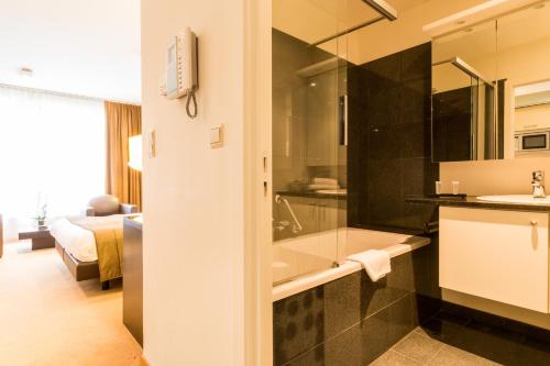 bagno con vasca e lavandino di Diamant Suites Brussels EU a Bruxelles