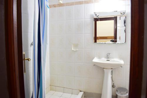 een witte badkamer met een wastafel en een spiegel bij Hotel Hellinis in Florina