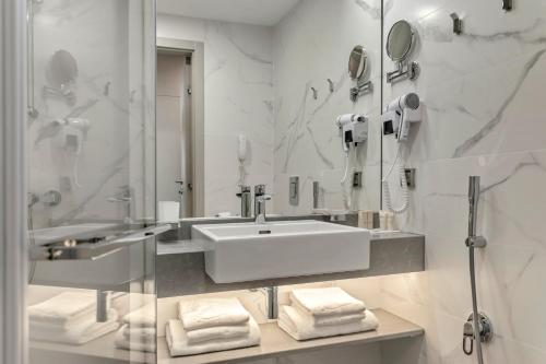 a white bathroom with a sink and a mirror at Hotel Bulgaria in Burgas City
