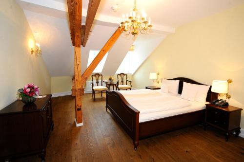 a bedroom with a large bed and a chandelier at HELIOPARK Bad Hotel Zum Hirsch in Baden-Baden