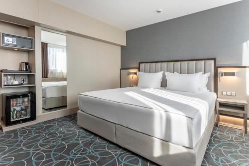 a bedroom with a large white bed and a fireplace at Hotel Bulgaria in Burgas City