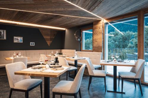 a restaurant with tables and chairs and a large window at Les Dolomites Mountain Lodges in San Martino in Badia