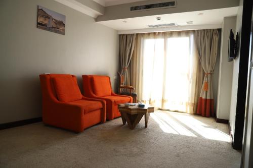 a living room with two orange chairs and a table at Citymax Hotel Aswan in Aswan