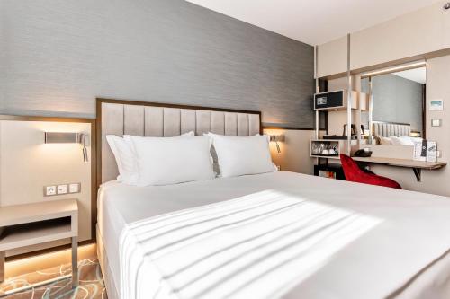 a bedroom with a large white bed and a red chair at Hotel Bulgaria in Burgas City