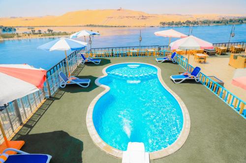 una piscina con sombrillas, sillas y agua en Citymax Hotel Aswan, en Asuán