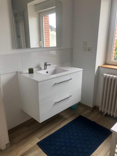 Un baño con un lavabo blanco y un espejo. en La Marandière, en Saint-Quay-Portrieux