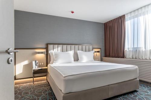 a bedroom with a large white bed and a window at Hotel Bulgaria in Burgas City