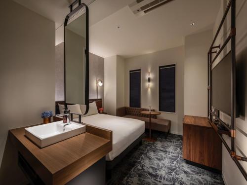 ein Hotelzimmer mit einem Bett, einem Waschbecken und einem Spiegel in der Unterkunft THE LIVELY HONMACHI OSAKA / Vacation STAY 76674 in Osaka