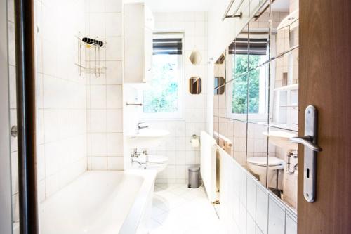 ein weißes Badezimmer mit einer Badewanne und einem Waschbecken in der Unterkunft Oberwiesenthal Apartments in Kurort Oberwiesenthal
