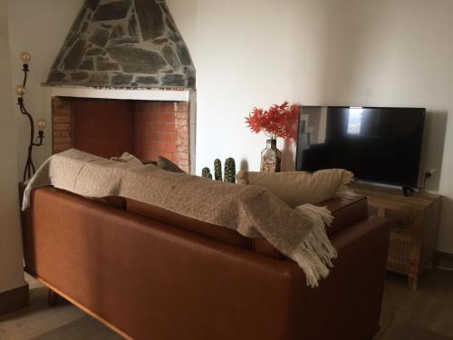 a living room with a brown couch and a fireplace at Lambisco- Alojamento local in Alfândega da Fé