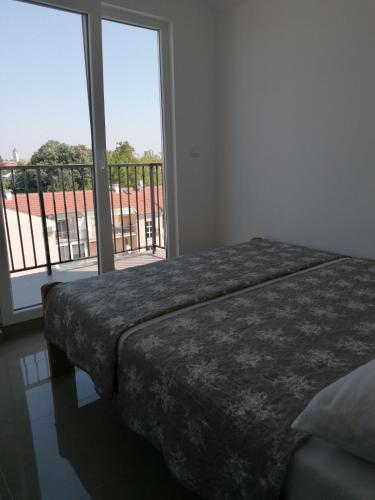 a bedroom with a bed and a large window at Djukic apartman in Šabac