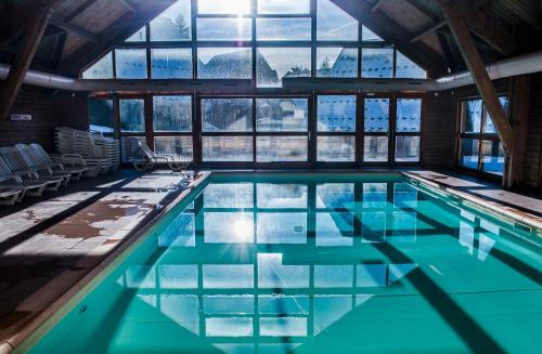 una piscina con acqua blu in un edificio con finestre di Flocons du Soleil by Actisource a La Joue du Loup