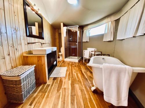 a bathroom with a bath tub and a wooden floor at ParkView Safari Lodge in Colchester