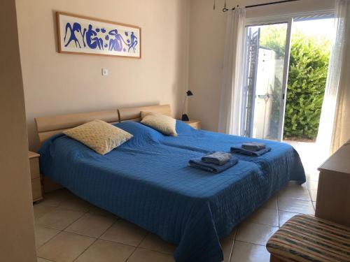a bedroom with a blue bed with towels on it at Limnaria Villas - comfy 2 bed, 2 bath ground floor apartment in Paphos