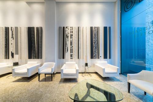 a lobby with white chairs and a glass table at Rede Andrade CWB in Curitiba