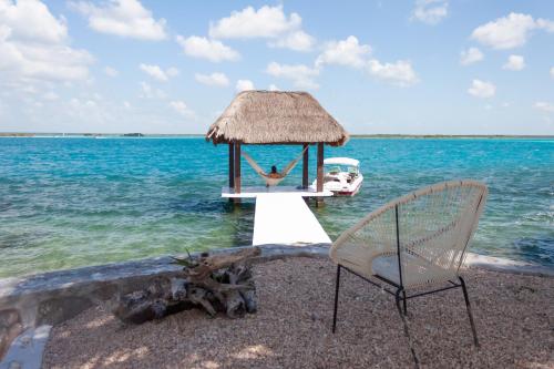 a couple of chairs sitting on a beach with the ocean at Costera 171 · Guest House in Bacalar