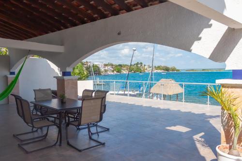 a patio with a table and chairs and a view of the water at Costera 171 · Guest House in Bacalar