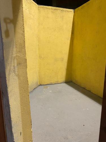 a corner of a room with a yellow wall at Hospedagem Mariano in Arraial do Cabo