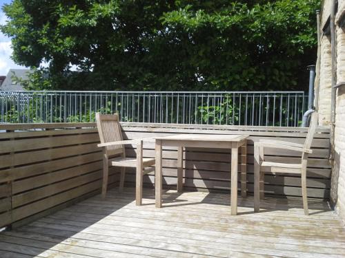 a wooden table and two chairs on a deck at Hotel Recour in Poperinge