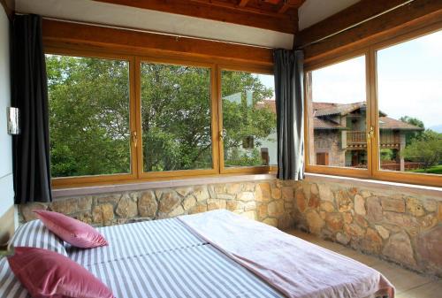 uma cama num quarto com janelas e uma parede de pedra em Apartamentos Armua em Zugarramurdi