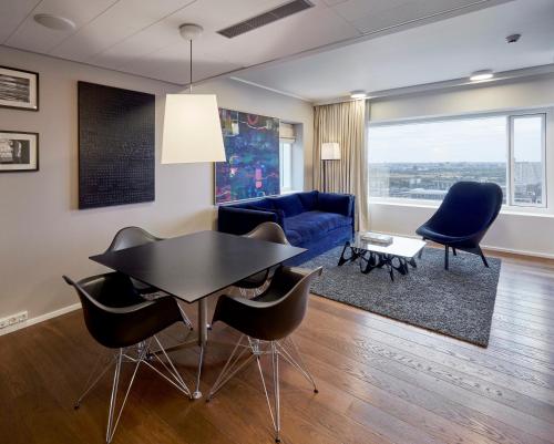 a living room with a table and chairs and a blue couch at Crowne Plaza Copenhagen Towers by IHG in Copenhagen