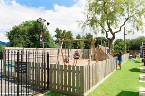a playground in a park with people playing on a swing at The Britannia Inn & Waves Restaurant in St Austell