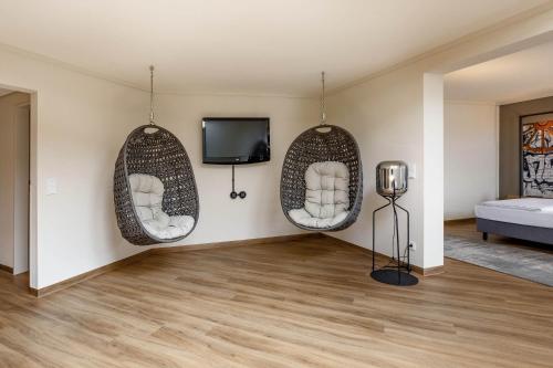 a living room with two hanging chairs and a tv at Seminaris Hotel Bad Boll in Bad Boll