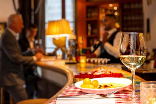 a table with a plate of food and a glass of wine at Hôtel Les Armures in Geneva