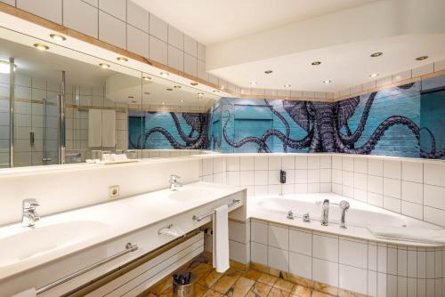 a bathroom with two sinks and an octopus mural at Seminaris Hotel Bad Boll in Bad Boll