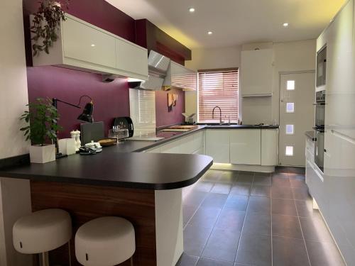 una cucina con armadi bianchi e parete viola di Milton Mews - Spacious and modern 3 bedroom apartment in Portsmouth a Portsmouth
