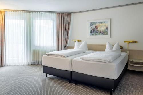 a bedroom with a large white bed with white pillows at Seminaris Hotel Bad Boll in Bad Boll
