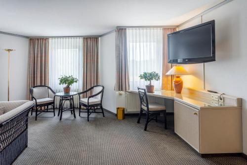a hotel room with a desk and a table with chairs at Seminaris Hotel Bad Boll in Bad Boll