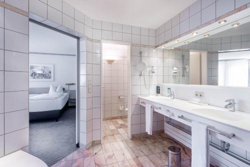 a bathroom with two sinks and a large mirror at Seminaris Hotel Bad Boll in Bad Boll