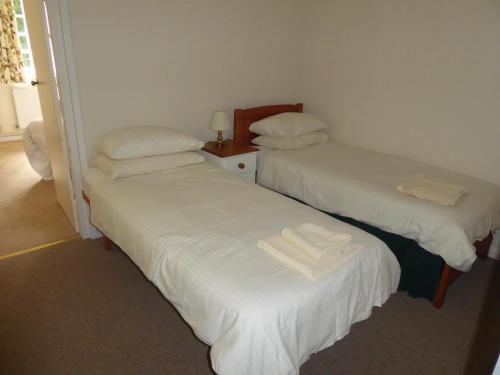 two beds in a room with white sheets and pillows at Lovelace in Porlock