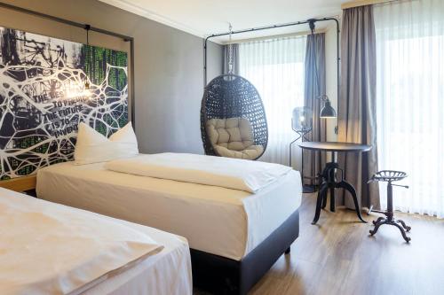 a hotel room with two beds and a chair at Seminaris Hotel Bad Boll in Bad Boll