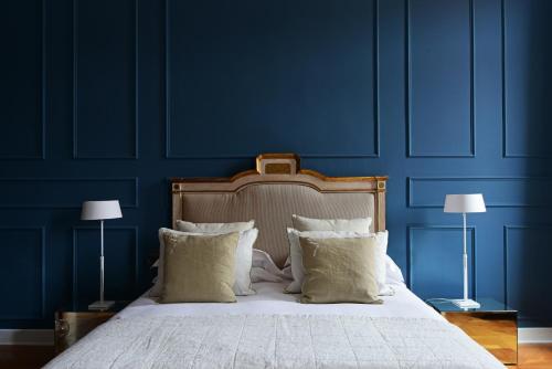 a blue bedroom with a bed with pillows and two lamps at The Presidential Suite in Trieste