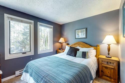 a bedroom with a bed with blue walls and two windows at Scandinavian Lodge in Steamboat Springs