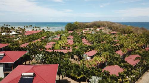 an aerial view of a resort with pink roofs and the ocean at Le Village de la Pointe in Le Vauclin