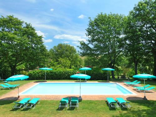 a swimming pool with blue chairs and umbrellas at Holiday Home Podere S Giovanni by Interhome in Casole dʼElsa