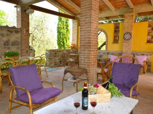 a patio with purple chairs and a table with a bottle of wine at Holiday Home Podere Rasenna by Interhome in Marti