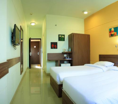 a hotel room with two beds and a tv at Ginger Pondicherry in Puducherry