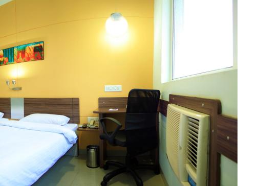 a bedroom with a bed and a desk and a chair at Ginger Pondicherry in Puducherry