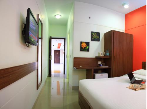 a bedroom with a bed and a television on a wall at Ginger Pantnagar in Pantnagar