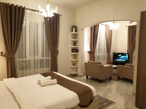 Muscat Royal Suites في سيب: غرفة نوم بسرير وتلفزيون وكرسي