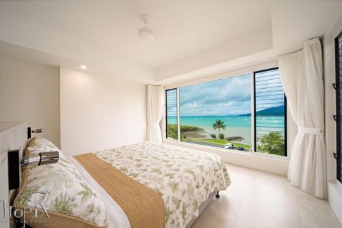 a bedroom with a large window with a view of the ocean at Splendeur Sur La Mer Premiere in Airlie Beach