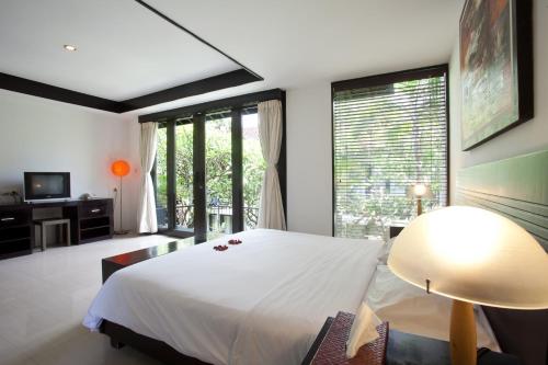 una camera da letto con un grande letto bianco e una grande finestra di S'cape Condotel a Sanur